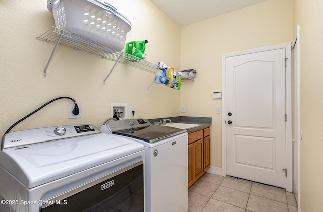 laundry room featuring washing machine and dryer, light tile patterned floors, cabinet space, and a sink