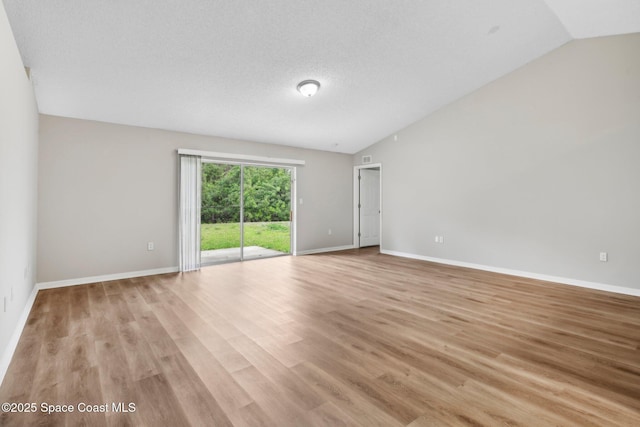 unfurnished room with a textured ceiling, baseboards, light wood-type flooring, and lofted ceiling