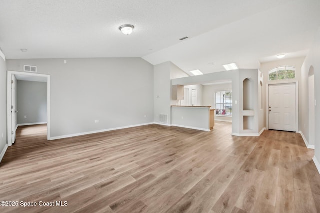 unfurnished living room with vaulted ceiling, light wood-style floors, visible vents, and baseboards