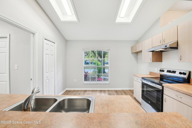 kitchen featuring under cabinet range hood, a sink, stainless steel electric range, light countertops, and vaulted ceiling