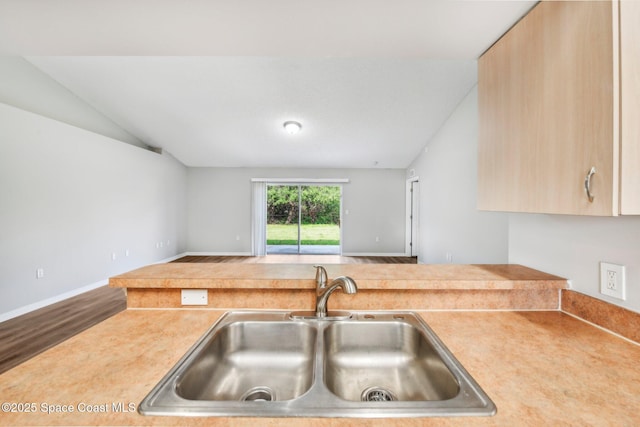 kitchen with vaulted ceiling, light countertops, open floor plan, and a sink