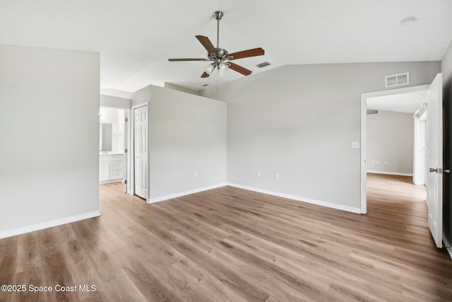 spare room with lofted ceiling, light wood-style flooring, baseboards, and visible vents