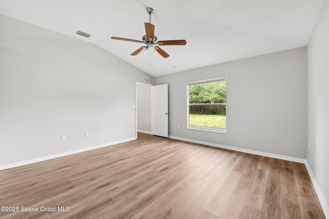 empty room with visible vents, baseboards, light wood-style floors, and vaulted ceiling