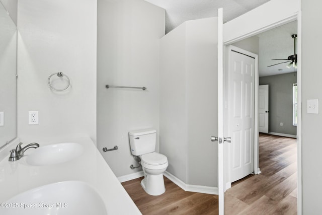 bathroom featuring toilet, wood finished floors, baseboards, and a sink