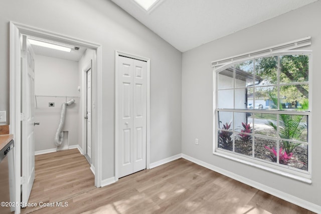 unfurnished bedroom featuring a closet, lofted ceiling, baseboards, and light wood-style flooring