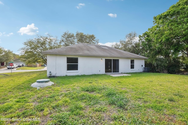 back of house with a yard, central AC unit, and stucco siding