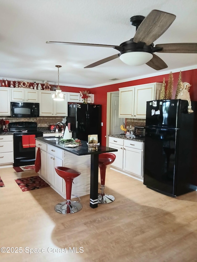 kitchen featuring dark countertops, decorative backsplash, black appliances, a ceiling fan, and a sink