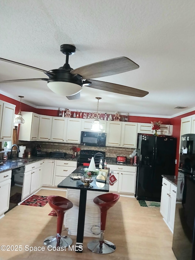 kitchen with dark countertops, backsplash, black appliances, and decorative light fixtures