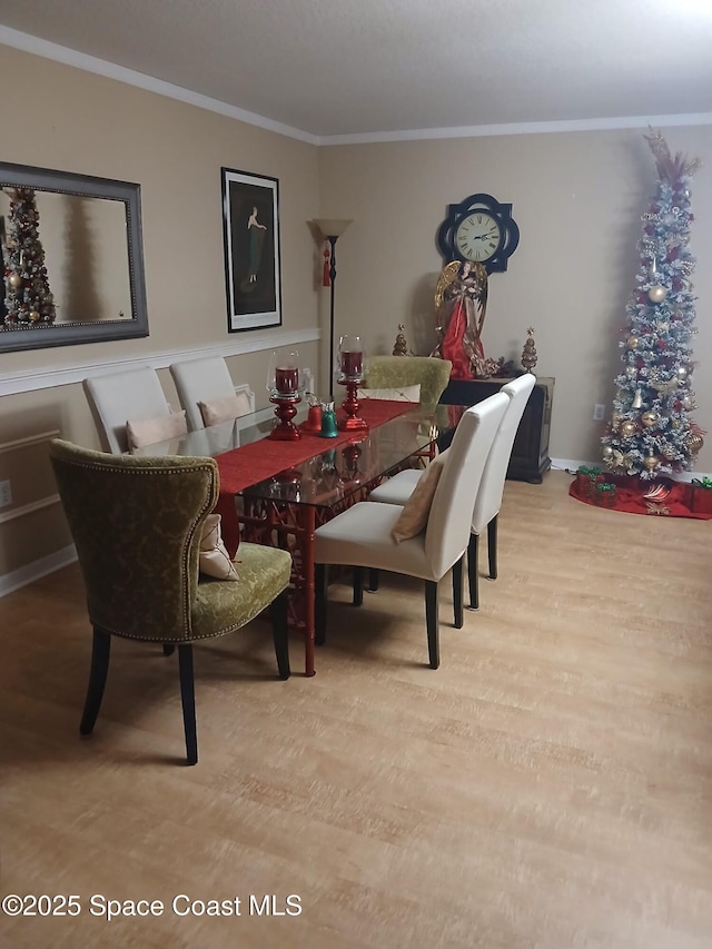 dining room featuring crown molding, wood finished floors, and baseboards