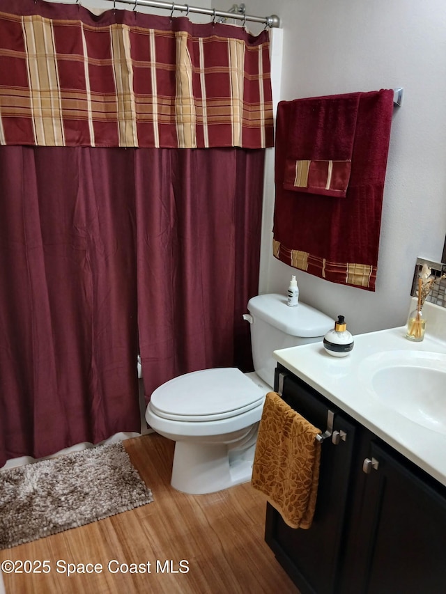 bathroom with curtained shower, toilet, vanity, and wood finished floors