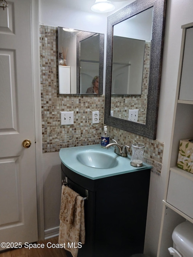 bathroom featuring vanity, decorative backsplash, and toilet