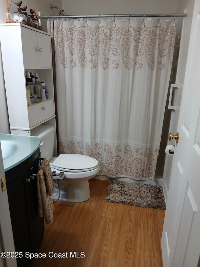 bathroom featuring vanity, a shower with shower curtain, toilet, and wood finished floors