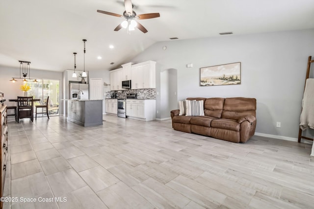 living area featuring visible vents, baseboards, ceiling fan, vaulted ceiling, and arched walkways