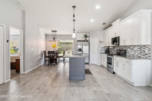 kitchen with white cabinetry, light stone countertops, backsplash, and stainless steel appliances