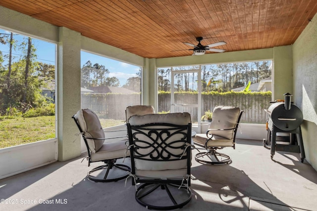 sunroom featuring wooden ceiling and a ceiling fan