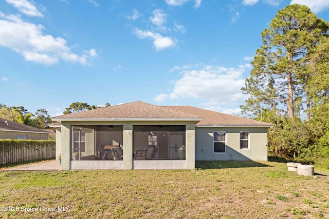 rear view of property featuring fence, roof with shingles, stucco siding, a yard, and a sunroom