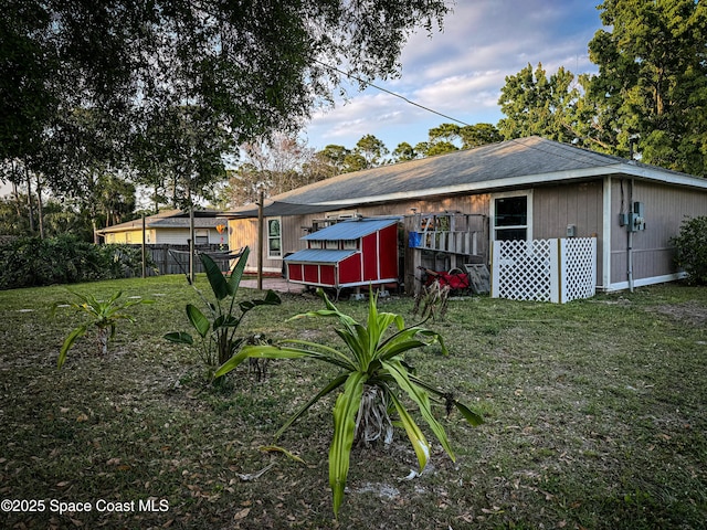 rear view of property with a yard, an outdoor structure, and fence