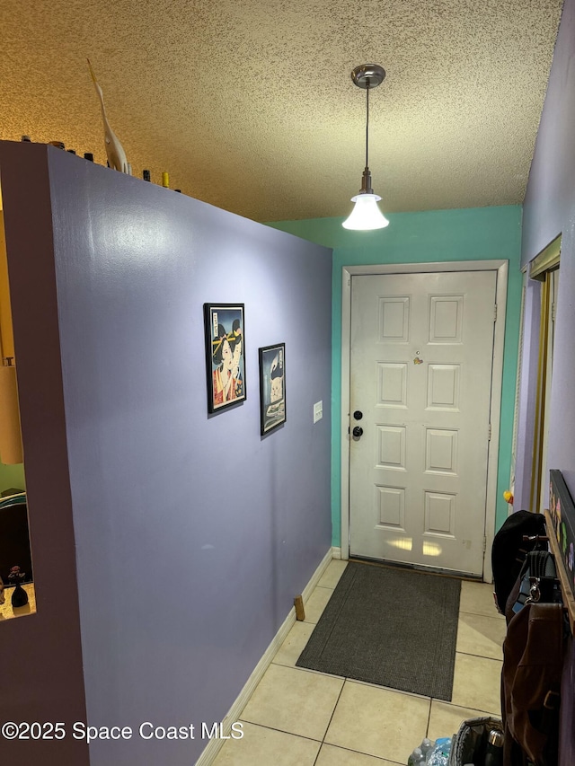 foyer featuring light tile patterned flooring, baseboards, and a textured ceiling