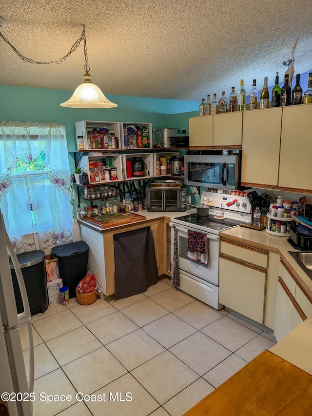 kitchen with stainless steel microwave, a textured ceiling, white electric range oven, light tile patterned floors, and hanging light fixtures