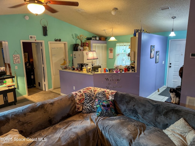 living room with lofted ceiling, a ceiling fan, visible vents, and a textured ceiling