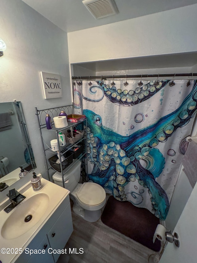 full bath featuring vanity, a shower with shower curtain, wood finished floors, visible vents, and toilet