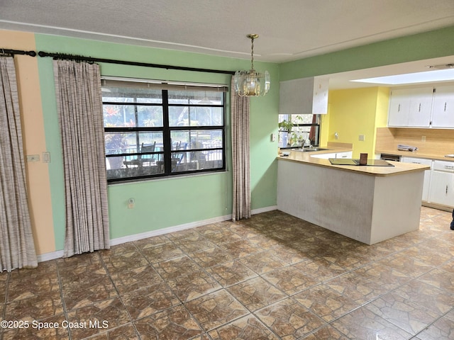 2001 Villa Espana Trl, Melbourne, FL 32935 - kitchen with an inviting chandelier, a peninsula, white cabinets, light countertops, and baseboards