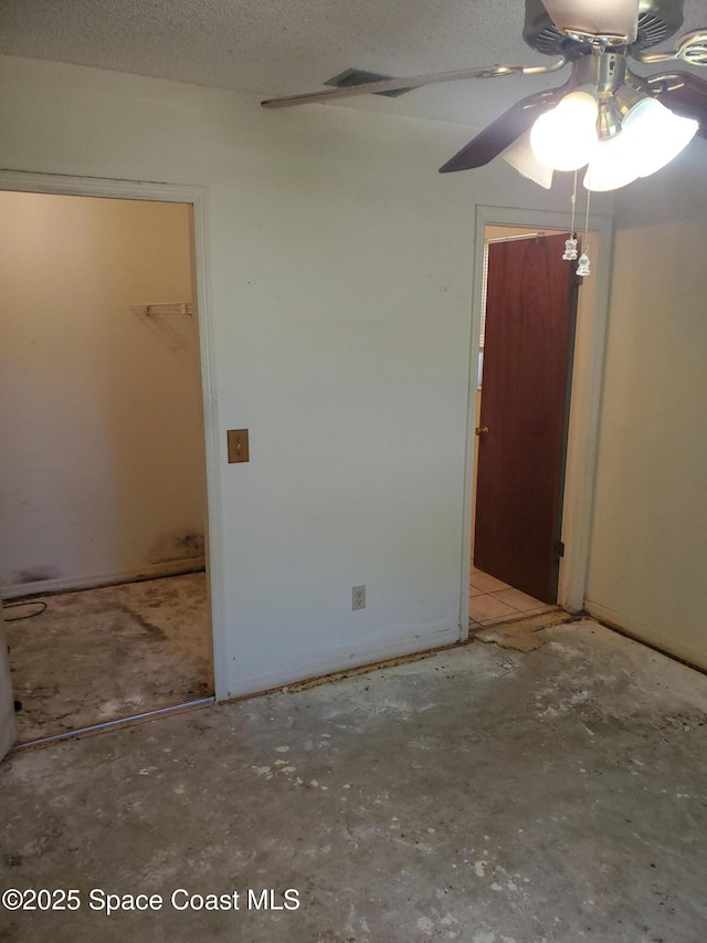 spare room featuring a textured ceiling, concrete floors, and ceiling fan