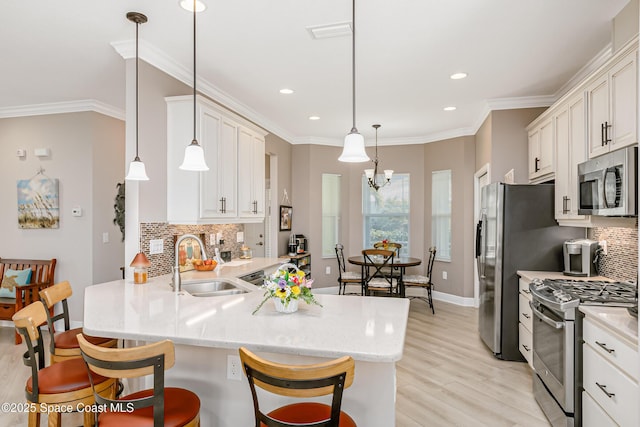 kitchen featuring ornamental molding, white cabinets, stainless steel appliances, and a sink