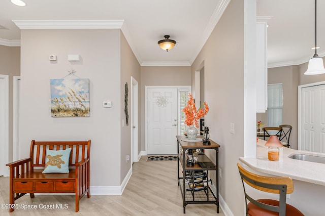 foyer featuring baseboards, light wood-style floors, and crown molding