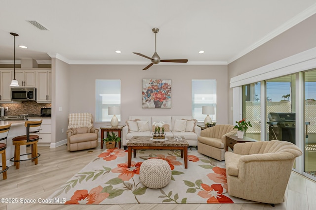 living room with recessed lighting, visible vents, light wood-style flooring, and crown molding