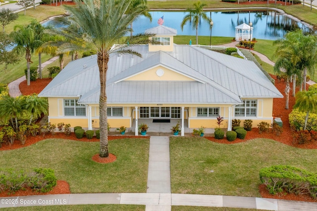 exterior space featuring a front lawn, metal roof, a water view, and stucco siding