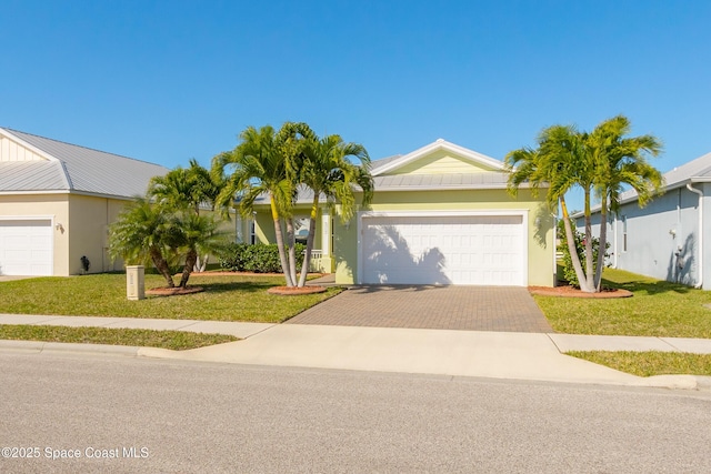 ranch-style home featuring a front lawn, decorative driveway, an attached garage, and stucco siding