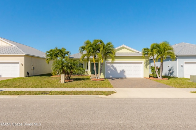 single story home featuring a front yard, stucco siding, metal roof, driveway, and an attached garage