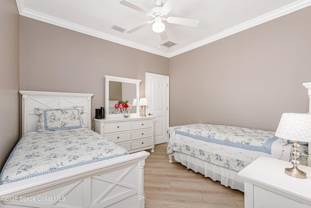 bedroom featuring visible vents, light wood-type flooring, crown molding, and a ceiling fan