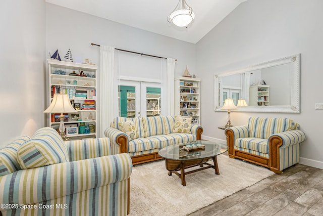 living area featuring french doors, baseboards, lofted ceiling, and wood finished floors