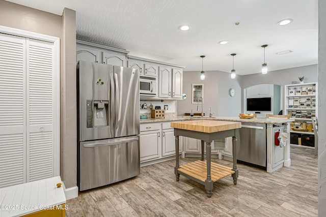 kitchen with light wood finished floors, a peninsula, recessed lighting, arched walkways, and appliances with stainless steel finishes