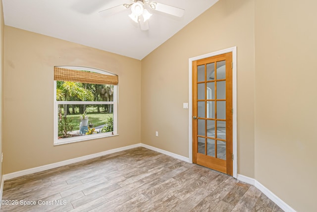 empty room featuring a ceiling fan, lofted ceiling, wood finished floors, and baseboards