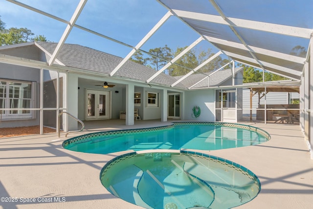 view of swimming pool with glass enclosure, a patio area, french doors, and a pool with connected hot tub