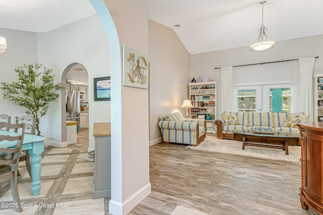 foyer entrance featuring baseboards, light wood-type flooring, arched walkways, and lofted ceiling