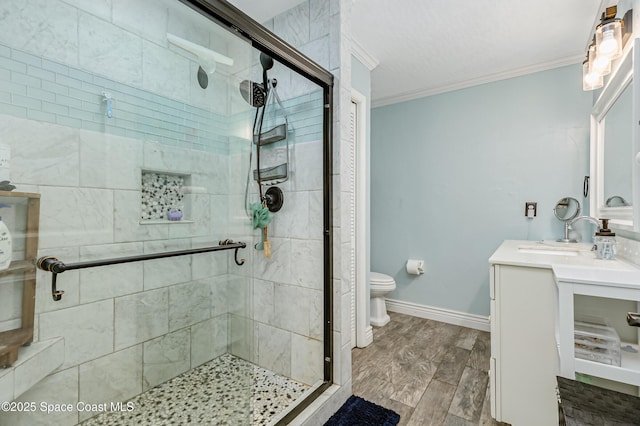 bathroom with vanity, wood finished floors, baseboards, ornamental molding, and a shower stall