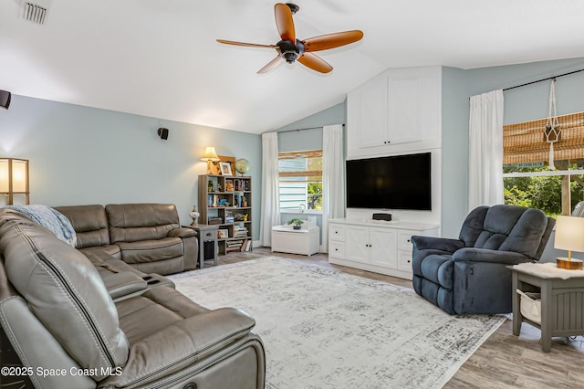 living area featuring vaulted ceiling, light wood-style flooring, visible vents, and ceiling fan