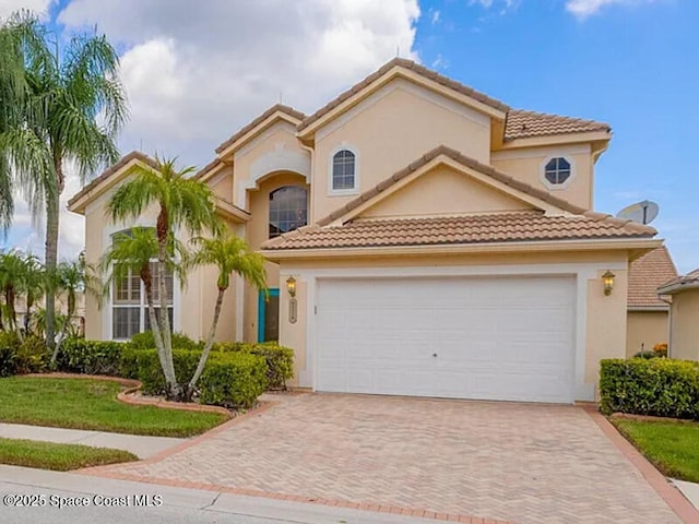 mediterranean / spanish house featuring a garage, decorative driveway, and stucco siding