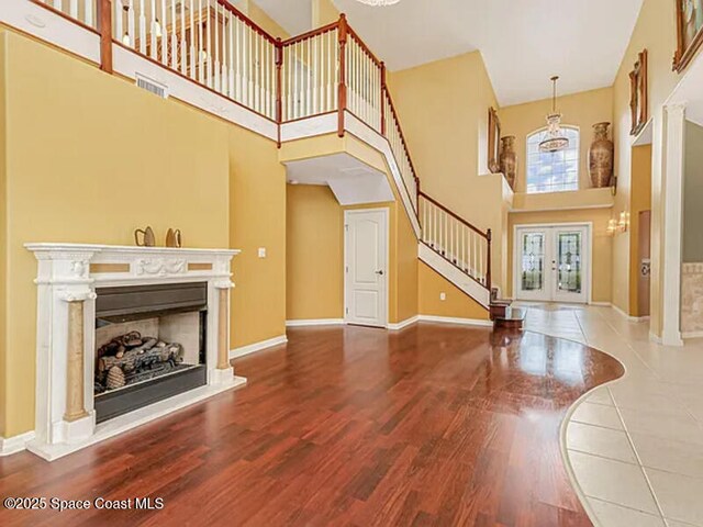 unfurnished living room featuring visible vents, a fireplace with raised hearth, stairs, and wood finished floors