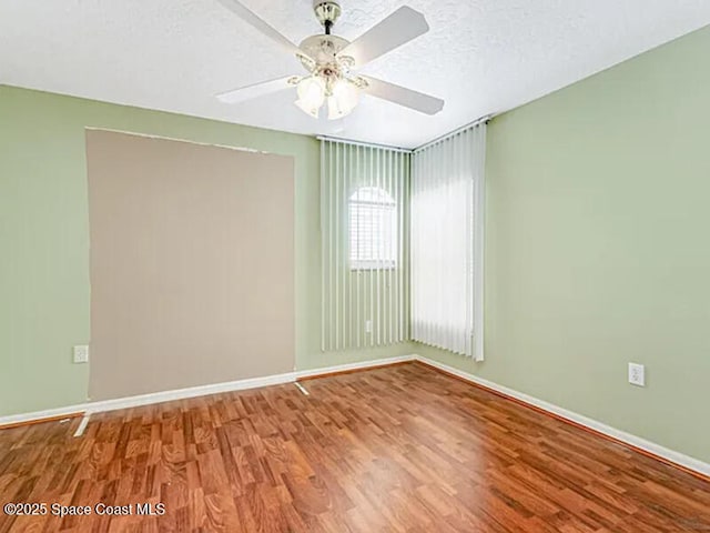 unfurnished room with ceiling fan, wood finished floors, baseboards, and a textured ceiling