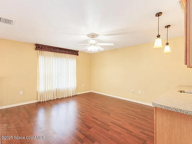 empty room featuring dark wood-style floors, visible vents, and baseboards