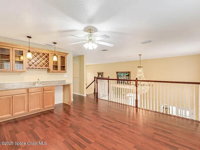 kitchen featuring pendant lighting, a sink, light countertops, glass insert cabinets, and dark wood-style flooring