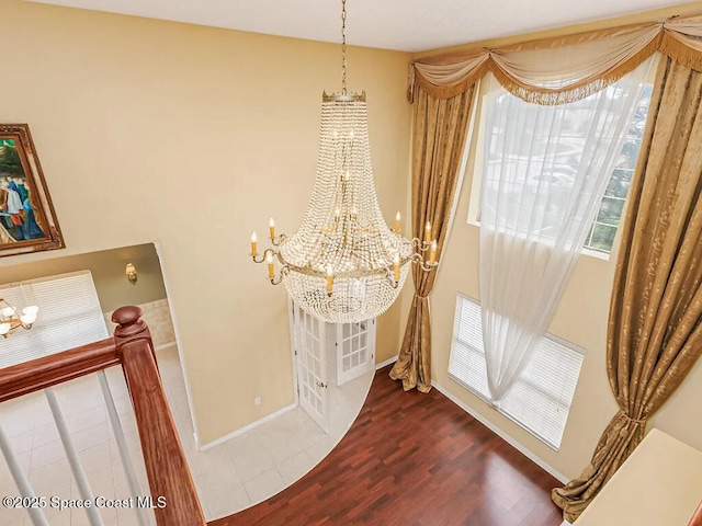 room details with baseboards, an inviting chandelier, and wood finished floors