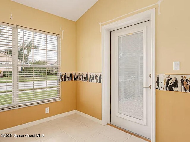 doorway to outside featuring light tile patterned floors, baseboards, and lofted ceiling