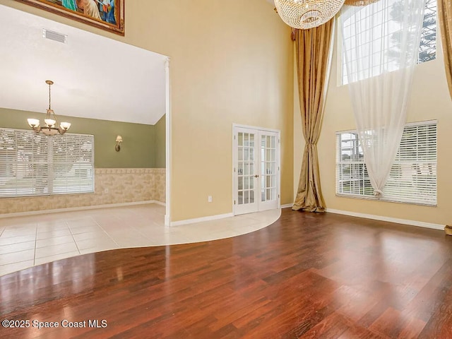 unfurnished living room with visible vents, a chandelier, french doors, a high ceiling, and tile patterned floors