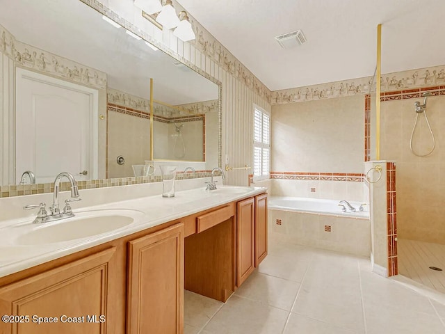 bathroom with tile patterned flooring, visible vents, a tile shower, and a sink